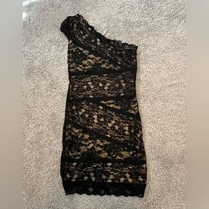 One shoulder black lace mini dress with tan liner underneath.